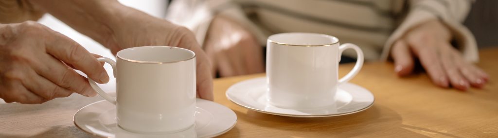 Image of two people's hands and two cups of tea sitting at a table