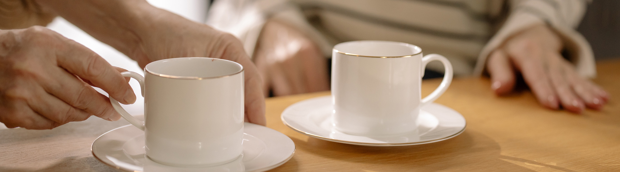 Image of two people's hands and two cups of tea sitting at a table