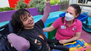 Girl in wheel chair raising arms and smiling